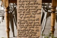 a bold wedding tablescape with a vintage table, bright blooms, a paper table runner and quotes, greenery and colorful glasses
