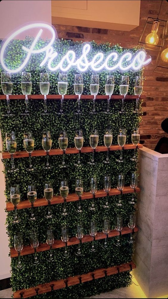 a boxwood wall with shelves-holders and a neon sign is a lovely modern idea to serve drinks at your wedding