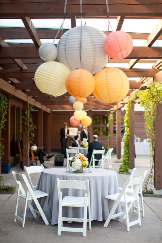 a bright outdoor wedding cocktail space with grey, yellow and coral paper lanterns of various sizes is fun and cute
