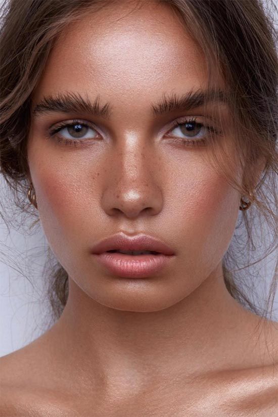 a bronze makeup with a shiny pink lip, shiny skin and bronzer, trendy eyebrows and coral blush is wow