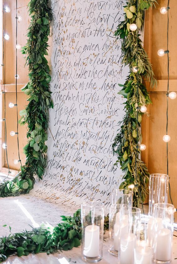 a calligraphy wedding ceremony backdrop with quotes, greenery and pillar candles is amazing for a wedding