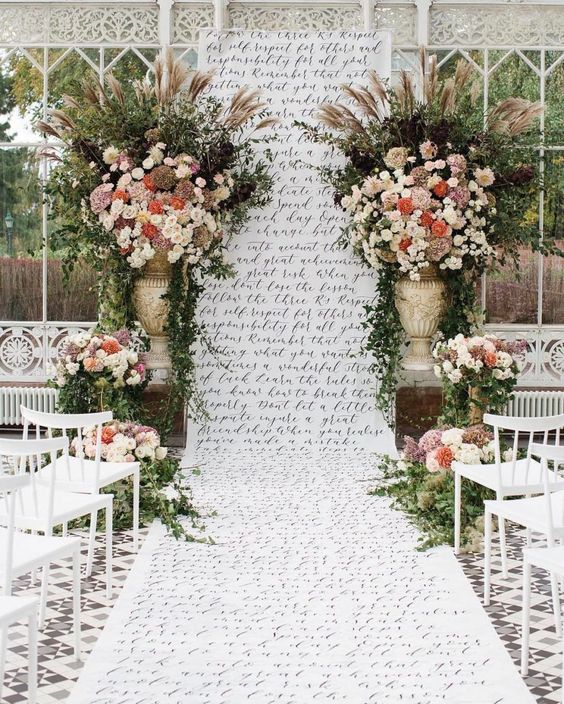 a catchy wedding backdrop with quotes, greenery and super lush blooms is a cool and lovely idea for a wedding
