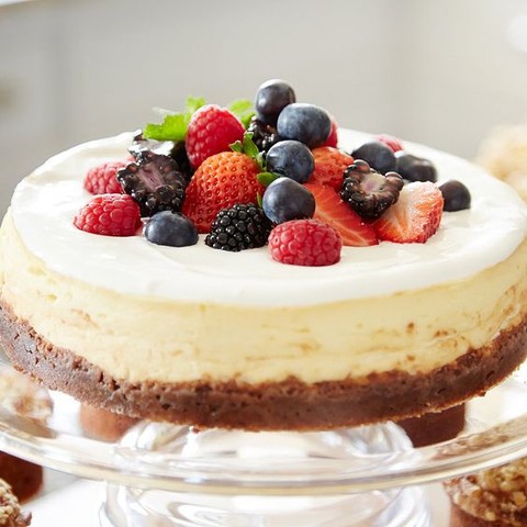 a cheesecake on a chocolate base topped with fresh berries is a crowd-pleasing wedding dessert idea