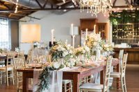 a chic indoor wedding reception with white florals, greenery, crystal chandeliers and flowy neutral linens is amazing