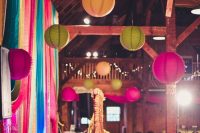 a colorful boho wedding reception space with bright paper lanterns and bold blooms, colorful ribbon and curtains is wow