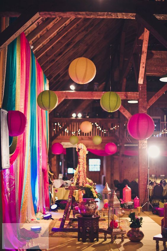 a colorful boho wedding reception space with bright paper lanterns and bold blooms, colorful ribbon and curtains is wow