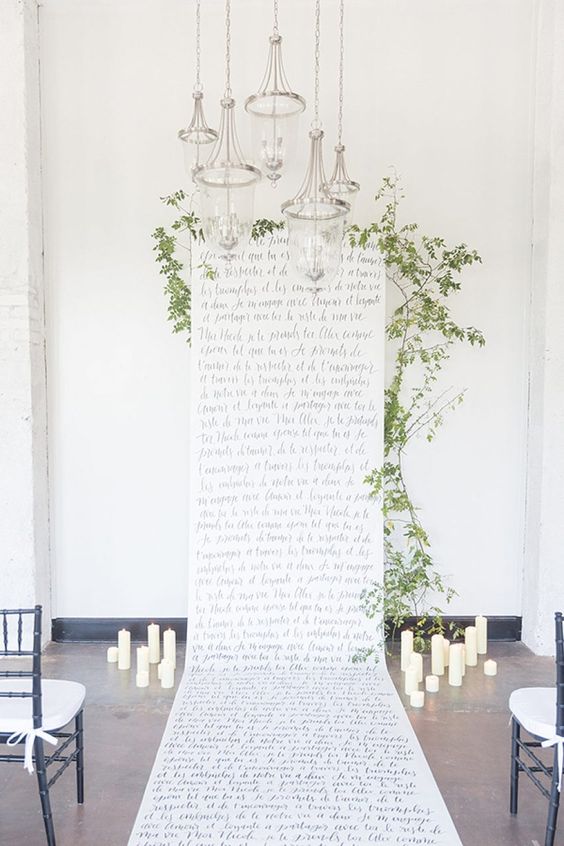 a cool quote wedding backdrop with black calligraphy, greenery, candles and pendant lamps is a cool solution
