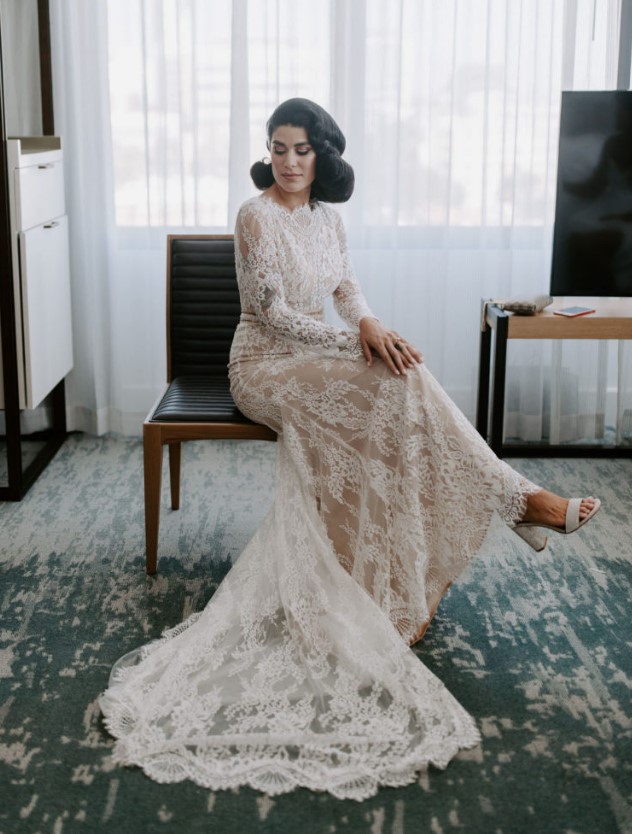 a creamy lace wedding dress with long sleeves, a high neckline, a trian and white block heels is ideal for an Old Hollywood wedding