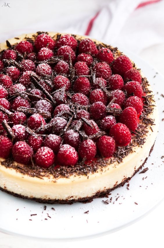 a dark chocolate raspberry cheesecake with a creamy, dark chocolate crust, topped with raspberry sauce, fresh raspberries and chocolate shavings