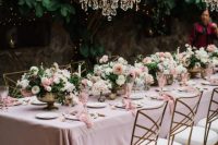 a fairy-tale wedding reception with blush linens and blooms, blush florals and lovely crystal chandeliers over the table setting