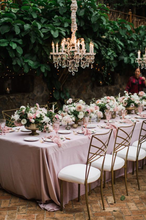 a fairy-tale wedding reception with blush linens and blooms, blush florals and lovely crystal chandeliers over the table setting