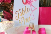 a glam hot pink wedding tablescape with bold blooms, matching planters, chargers and a lovely pink flamingo table number