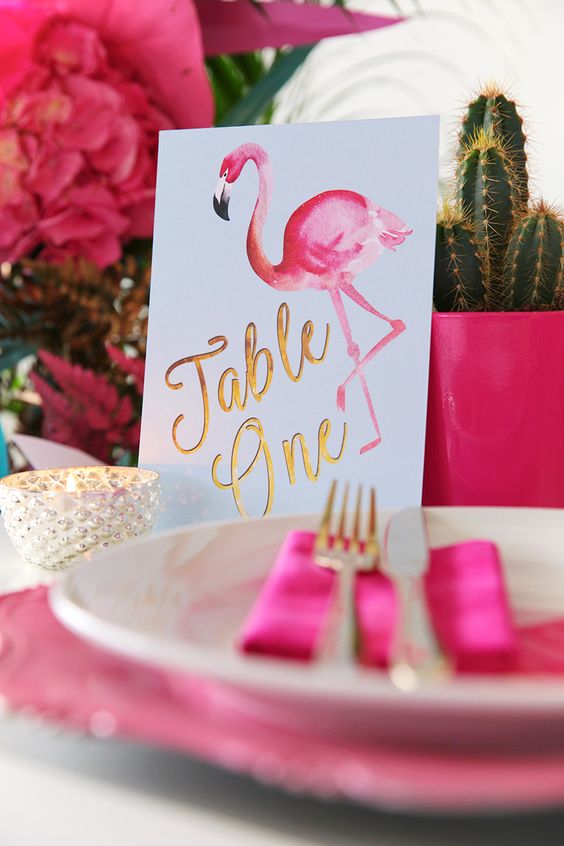 a glam hot pink wedding tablescape with bold blooms, matching planters, chargers and a lovely pink flamingo table number
