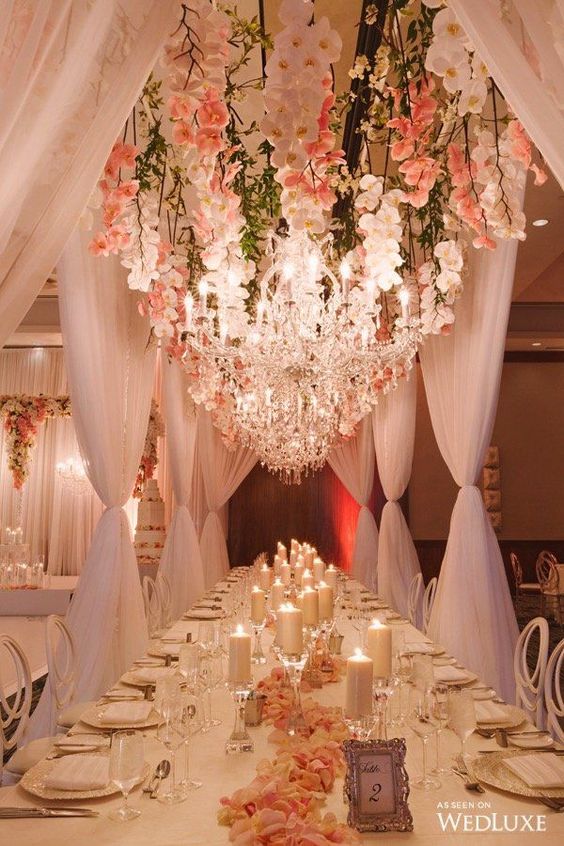 a jaw-dropping indoor wedding reception made outdoorsy with lush orchids hanging down and large glam crystal chandeliers is amazing