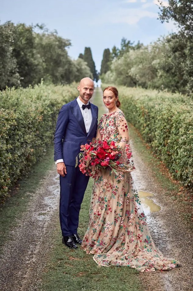 a jaw-dropping nude A-line wedding dress with bell sleeves with bold burgundy and blush floral embroidery all over the dress