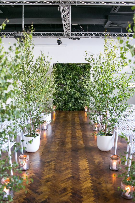 a living greenery wall and potted trees turn the indoor ceremony space into a forest