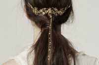 a messy low ponytail with a gold floral hair vine with long chains and rhinestons