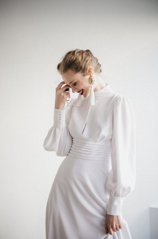 a modern take on a vintage wedding dress   a plain turtleneck Victorian inspired wedding gown with long sleeves and tassel earrings