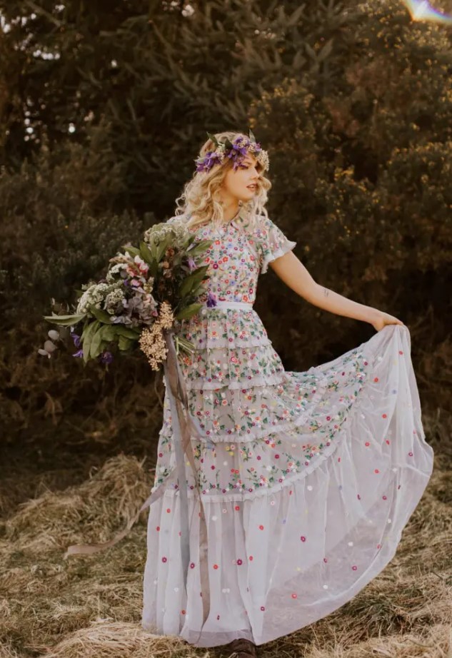 a neutral A-line wedding dress with colorful floral embroidery all over and short sleeves plus a floral crown