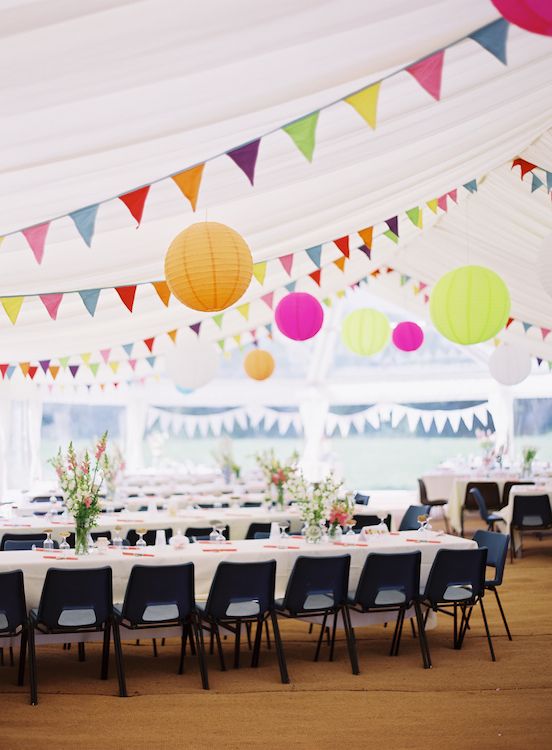 a neutral wedding reception space with bold blooms and colorful banners and paper lanterns is a lovely and vivacious space
