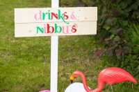 a planked sign, paper pompoms and a pink flamingo for cool and glam wedding decor, DIY it easily