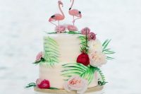 a pretty and bold wedding cake decorated with painted and real tropical leaves, blush and burgundy blooms and pink flamingos on top