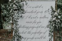a quote wedding backdrop with greenery and white blooms is a lovely outdoor or indoor wedding idea