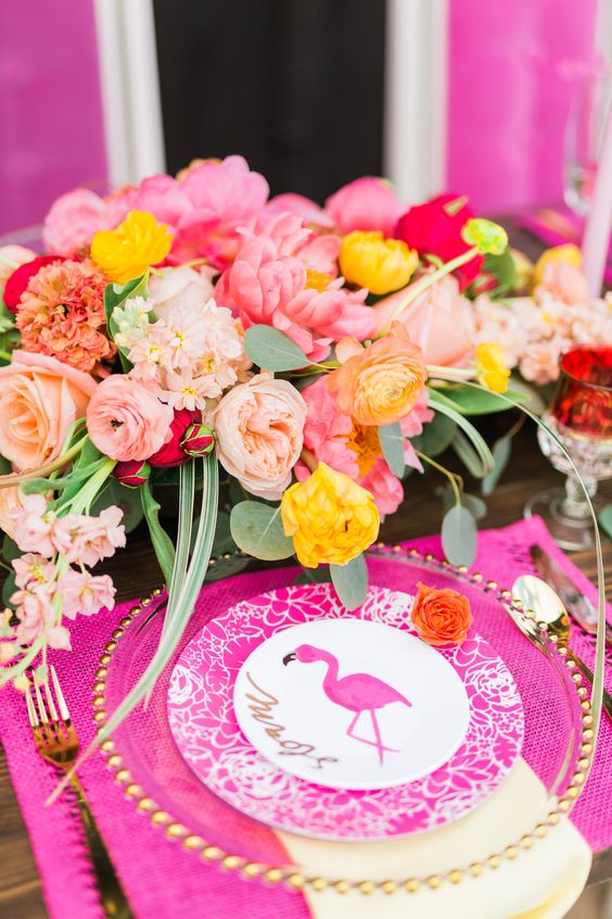 a super bright wedding place setting with bold blooms, hot pink accessories, a pink flamingo menu and card is wow