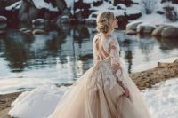 a tan wedding ballgown with white lace appliques and a tiered skirt with a train stands out in the snow