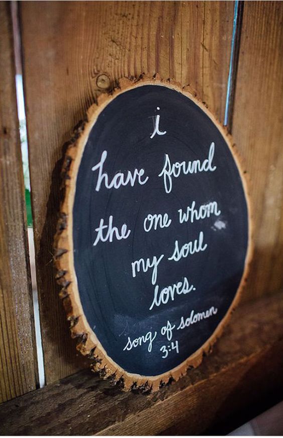 a tree slice chalkboard sign with white calligraphy, with a quote to decorate your wedding