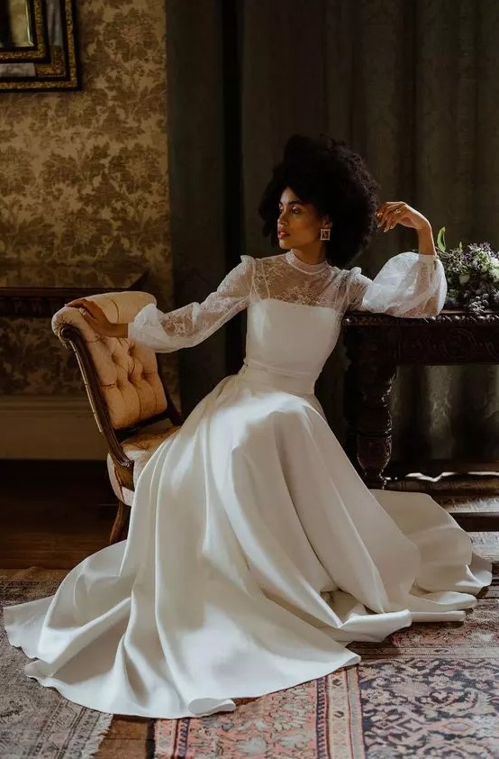 a vintage inspired A line plain and lace wedding dress with a turtleneck, puff sleeves, a train, statement earrings and a bold lip