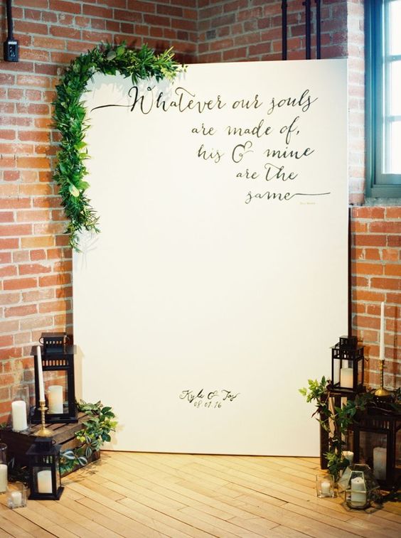 a wedding backdrop with a quote, greenery, candle lanterns and greenery is a cool and catchy indoor wedding decor idea