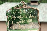 a whimsical mirror in an ornated frame, with gold calligraphy and greenery is a cool and chic decor idea
