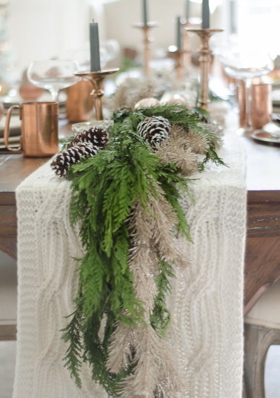 a white knit wedding table runner, an evergreen and white runner, snowy pinecones and grey candles are amazing for winter home decor