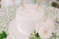 a white textural wedding cake topped with gold glitter geometric flamingos is amazign and very glam-like