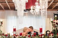 an enchanted wedding reception with lots of greenery and white blooms, a sequin tablecloth and lots of crystal chandeliers that steal the show