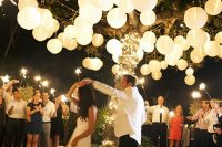 an outdoor dance floor with a living tree covered with string lights, paper lanterns all over for a lovely look