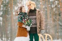 an outdoor groom’s look with a brown printed sweater, emerald jeans, mustard boots, a brown puffer jacket and a fux hat
