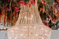 fantastic wedding decor – an oversized glam crystal chandelier surrounded with super bold and lush florals and greenery is wow