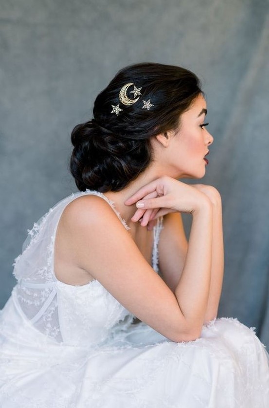 gold moon and star hair pins highlight this low updo giving it a romantic and fresh look
