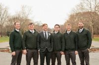 groomsmen wearing grey pants, white shirts, grey ties, green cable knit cardigans and brown shoes at a casual fall wedding
