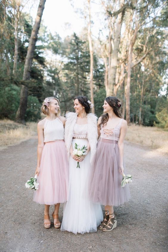 mismatching bridesmaid ensembles with white and nude lace up crop tops, a dusty pink and a pink tulle midi skirt for a boho wedding