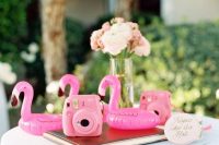 pretty retro wedding decor with pink flamingo floats, a pink camera and some neutral blooms is a chic and fun idea