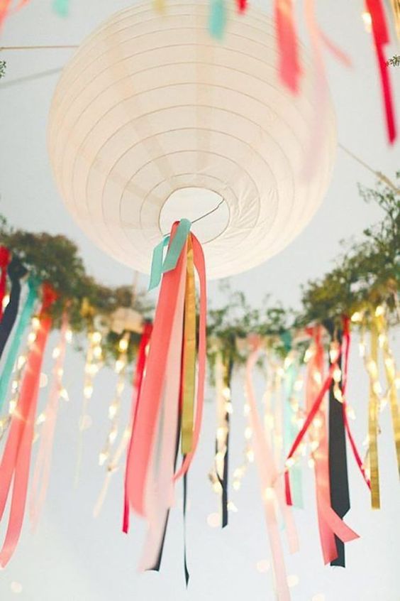white paper lanterns decorated with colorful ribbon, with string lights and greenery are great for styling a wedding reception