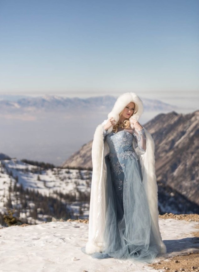 Elsa-inspired bridal look with a blue embellished wedding dress with long sleeves and an illusion neckline plus a faux fur coverup with a hood