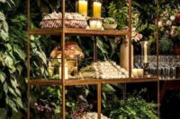 a beautiful brass shelving unit with candles and greenery plus blooms is a cool alternative to a usual wedding table