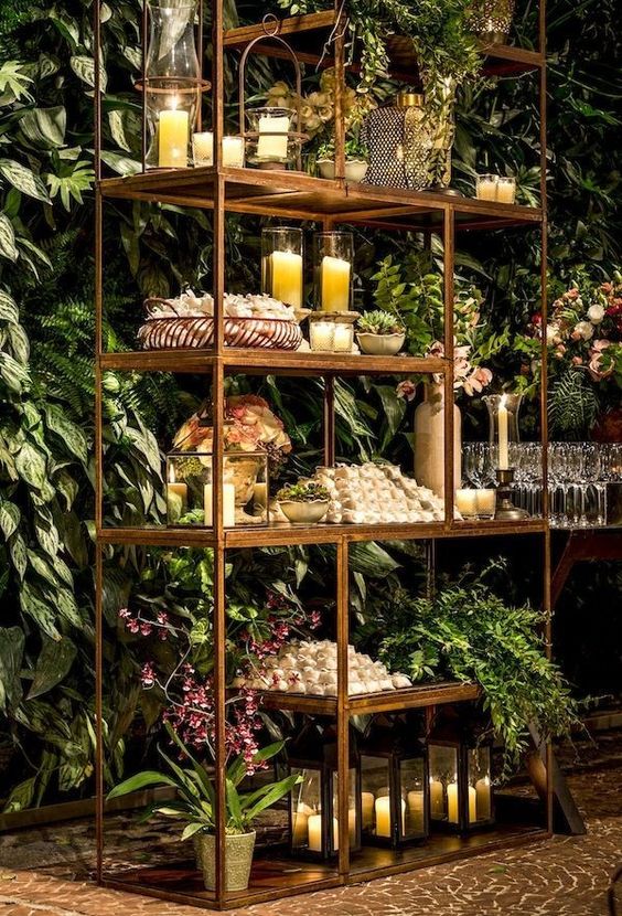 a beautiful brass shelving unit with candles and greenery plus blooms is a cool alternative to a usual wedding table