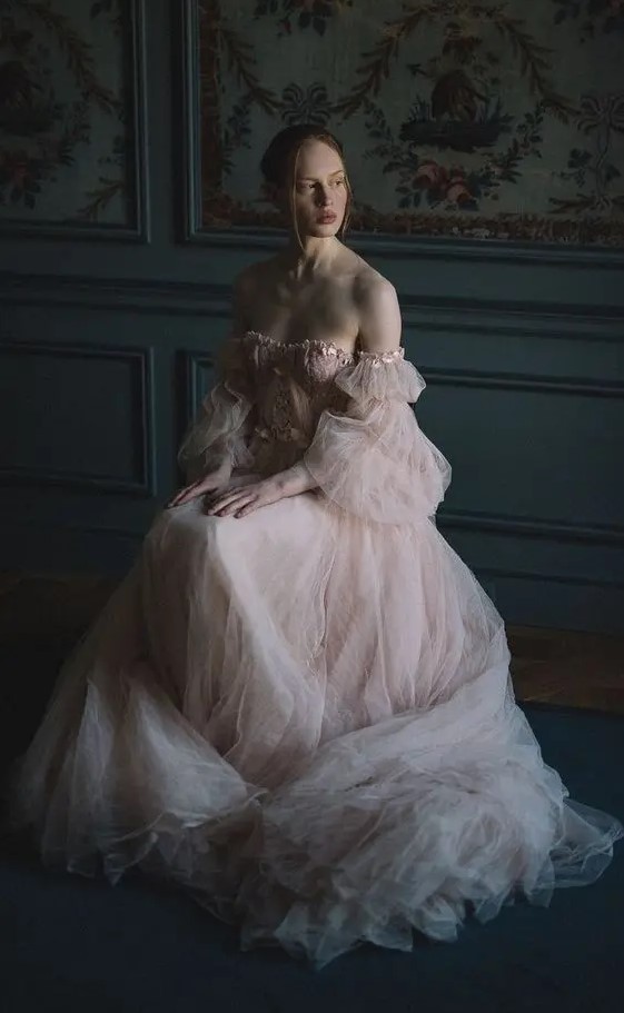 a blush off the shoulder tulle wedding dress with a lace corset and puff sleeves is a very romantic gown