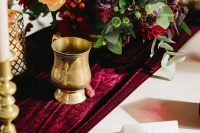 a bold and refined wedding tablescape with a marsala velvet runner and bold marsala blooms and berries is amazing for fall