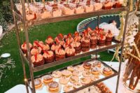 a brass stand with glass shelves is a cool idea of a wedding dessert table, and it can be used as an addition to it, too